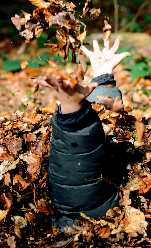 Kind wirft Blätter in die Luft