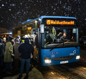 Busse bei der Romantischen Waldweihnacht Bus im Dunkeln im Schnee mit Menschen