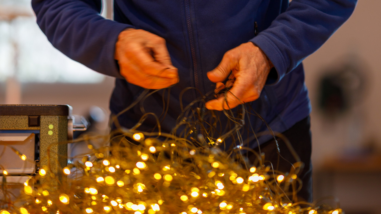 Reparaturhelfer untersucht eine Leuchtende Lichterkette