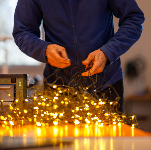 Ein Reparaturhelfer untersucht eine leuchtende Lichterkette