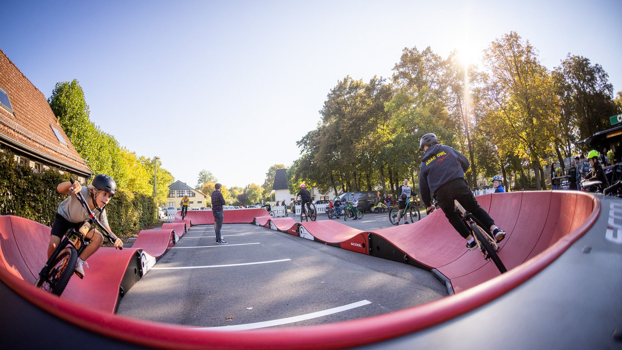 zwei Menschen auf Fahrrädern fahren über einen roten geschwungenen Parcours
