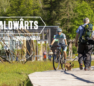 WALDWÄRTS am HdN Das Bild zeigt einen Mountainbiker und Wanderer vor dem Haus der Nachhaltigkeit