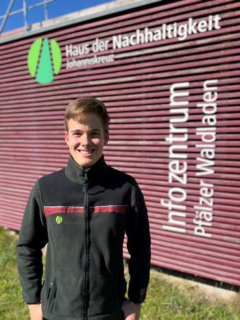 junger Mann in Landesforsten-Jacke vorm Haus der Nachhaltigkeit