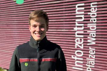 junger Mann in Landesforsten-Jacke vorm Haus der Nachhaltigkeit