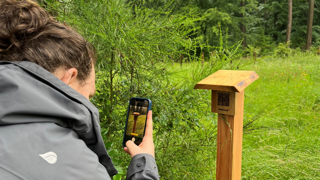 Frau scannt QR-Code auf Holz mit Handy ab