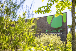 Schriftzug an Holzwand mit grünen Sträuchern