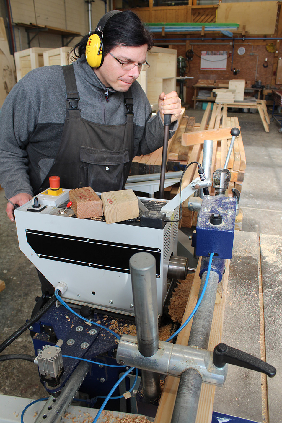An einer Maschine werden Teile der Holzbank bearbeitet.