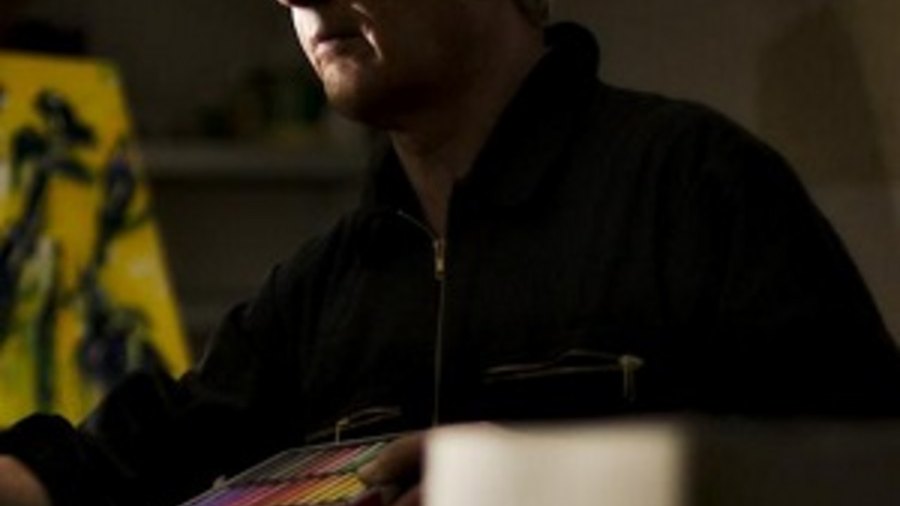 Mann in schwarzer Kleindung und Farbe malt