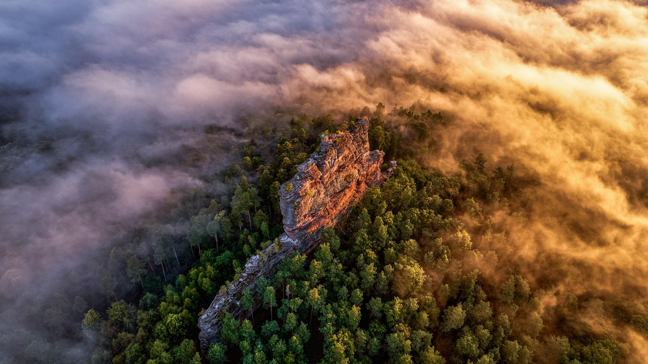 Der Fels Asselstein ist von oben zu sehen, im Nebel bei schräg einfallendem Sonnenlicht