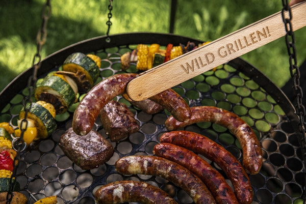 Grillzange hält Wurst über Rost