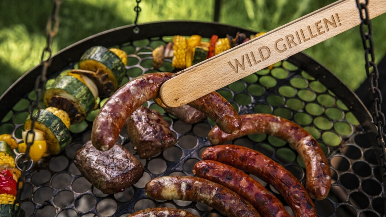 Grillzange hält Wurst über Rost