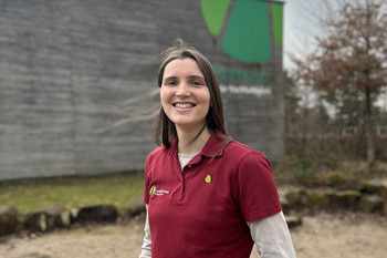 Das Bild zeigt eine lächelnde Mitarbeiterin im Außenbereich des Hauses der Nachhaltigkeit
